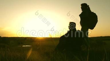 山顶上的旅行者男女在日落时欣赏风景。 情侣旅行者带着背包旅行。 Hik女孩